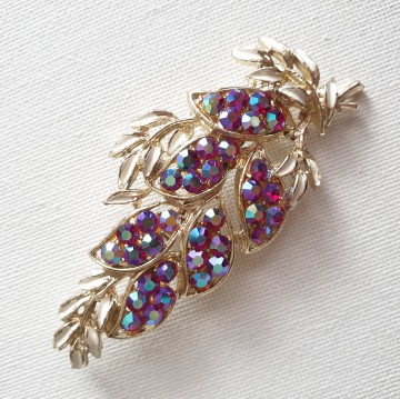 Licht goudkleurige bladvormige broche met wit emaille blaadjes en donkerrode aurora borealis strass