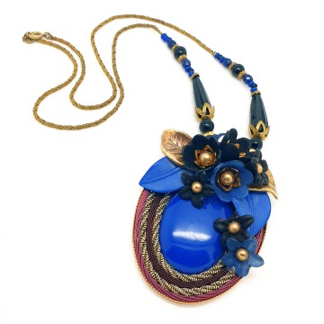 Early 20th century necklace with oval pendant plastic cabochon and flowers in the colours blue gold and black surrounded by dark red and goldtone cord - Bliinkt