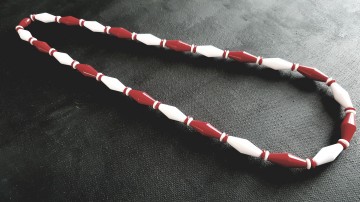 Avon 'Classic Lines'rood met witte plastic ketting uit 1989 op zwart