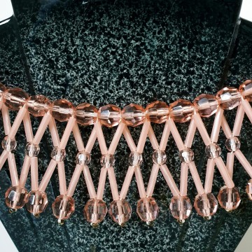 'Collar' ketting met drie rijen oudroze gefacetteerde ronde glaskralen met daartussen langwerpige plastic kralen op vaas