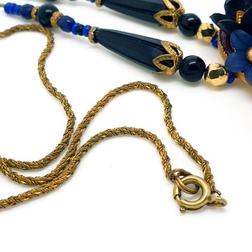 Early 20th century necklace with oval pendant plastic cabochon and flowers in the colours blue gold and black surrounded by dark red and goldtone cord - Bliinkt