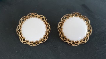 Emmons grote witte ronde oorbellen van platte plastic cabochons met goudkleurige filigrain rand en achtEmmons grote witte ronde oorbellen van platte plastic cabochons met goudkleurige filigrain rand en achterkant op zwarterkant