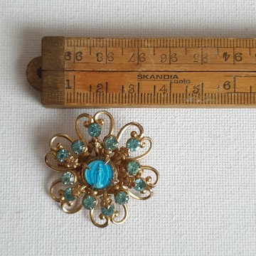 Flower shaped goldtone brooch with turquoise rhinestones and virgin