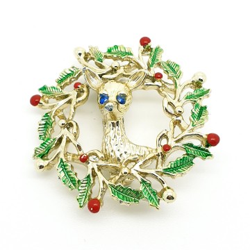 Gerrys goldtone Christmas wreath brooch with green enamel leaves and a deer with blue rhinestone eyes