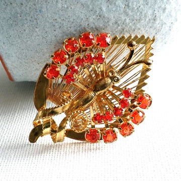 Goldtone butterfly sitting on wired leaf with red rhinestone wings - brooch