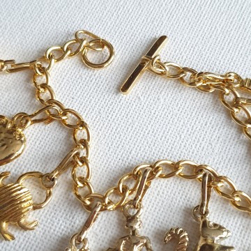 Goudkleurige bedelarmband met tien bedeltjes en T-sluiting