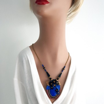 Early 20th century necklace with oval pendant plastic cabochon and flowers in the colours blue gold and black surrounded by dark red and goldtone cord - Bliinkt