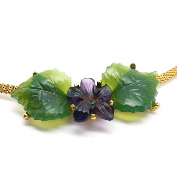 Kettinkje met plastic paars bloempje met strasssteentje en groene bloemblaadjes close-up