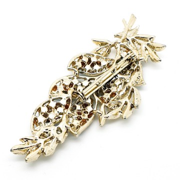 Licht goudkleurige bladvormige broche met wit emaille blaadjes en donkerrode aurora borealis strass