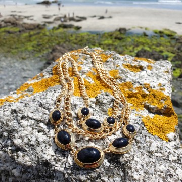 Monet goudkleurige 3 rijige 80s ketting met zwarte cabochons op muur in cornwall
