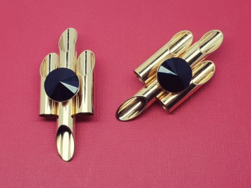 Grote goudkleurige panfluitachtige oorbellen met in het midden en zwarte plastic seen 60's op rood doek