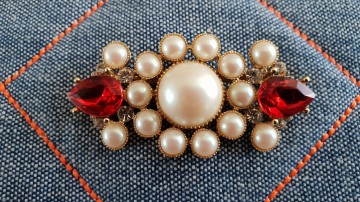 Richelieu goudkleurige broche met faux parels en rode druppelvormige strass op stof